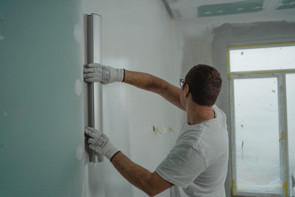 Plasterer flattening a freshly plastered wall